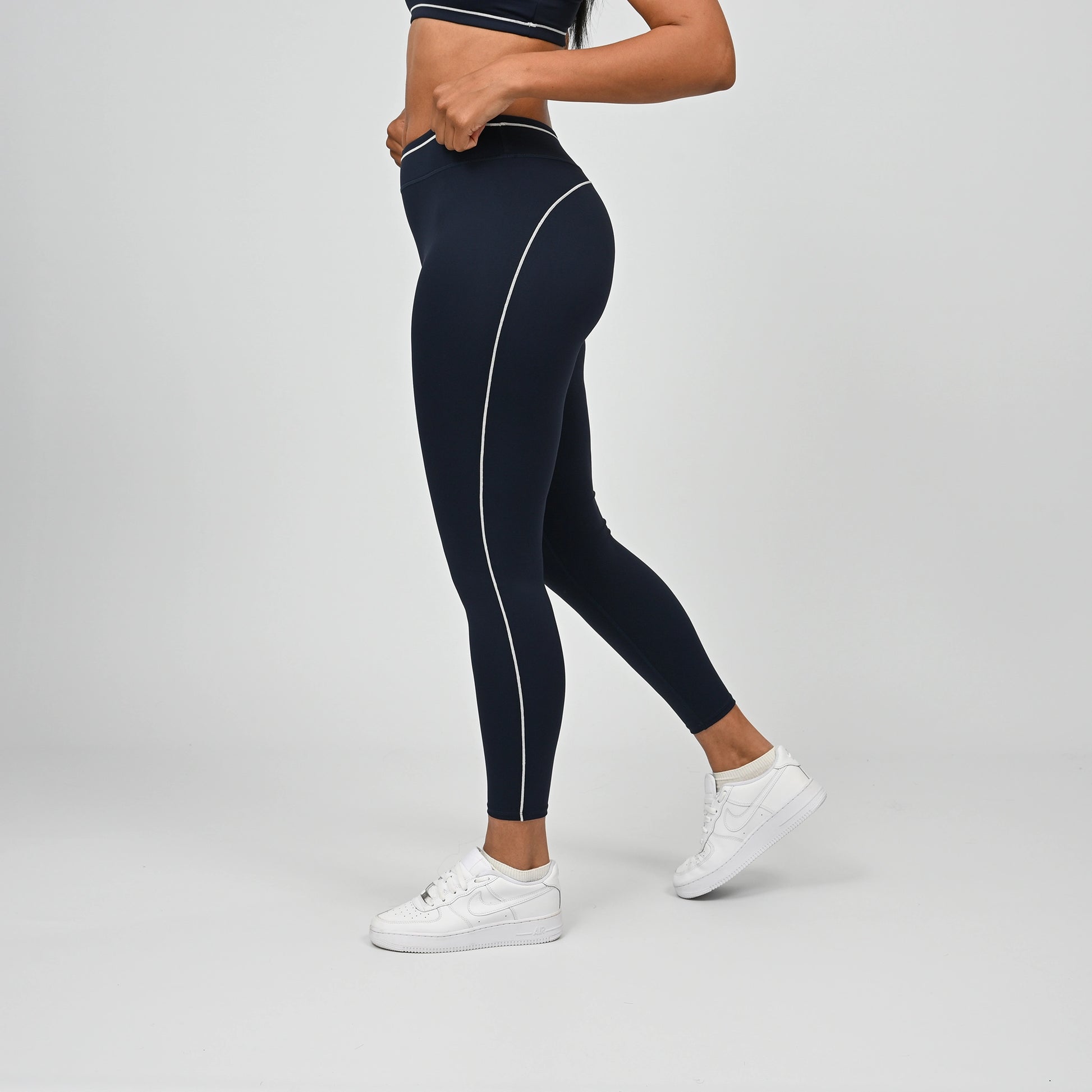 Hybrid yoga athlete wearing a navy crossfit gym outfit with white stripes on a gray background from Hybryd