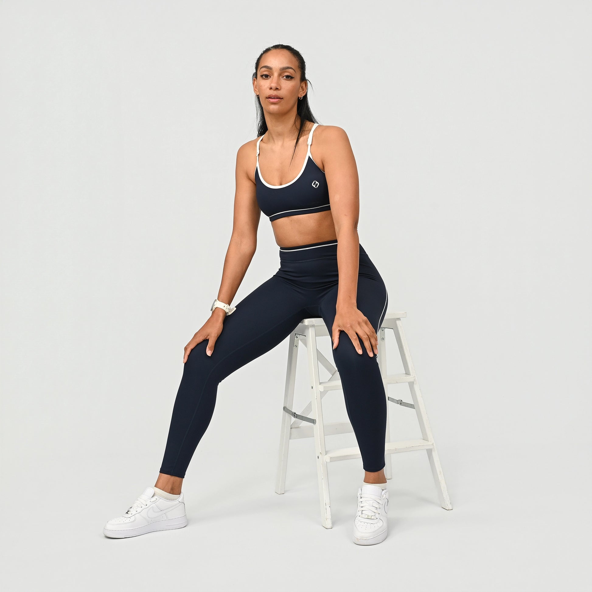 Hybrid yoga athlete wearing a navy crossfit gym matching set with white stripes on a gray background from activewear brand Hybryd