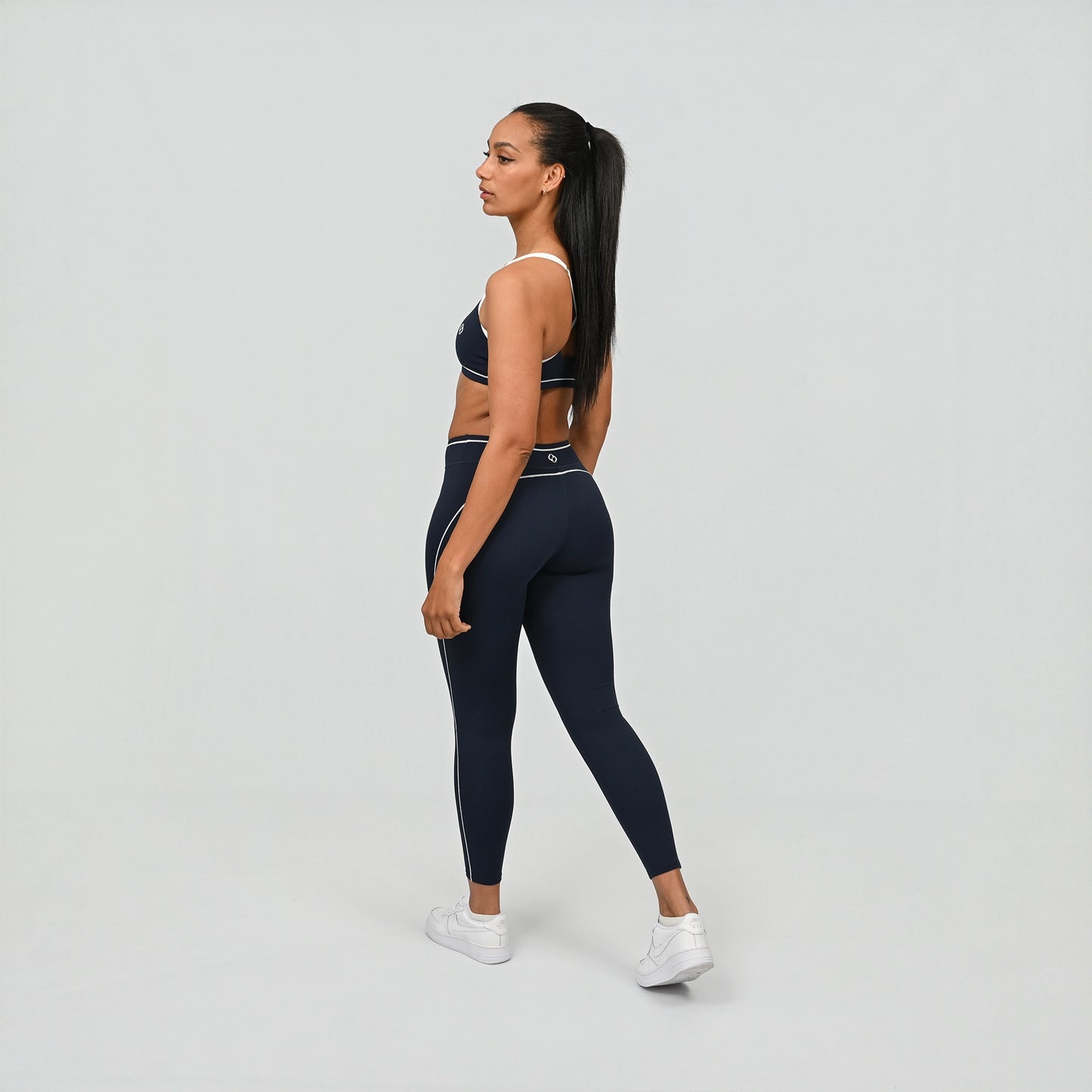 Hybrid yoga athlete wearing a navy crossfit gym matching set with white stripes on a gray background from Hybryd
