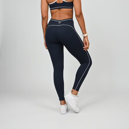 Hybrid yoga athlete wearing a navy crossfit gym outfit with white stripes on a gray background