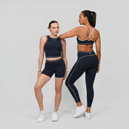 Two Female crossfit athlete wearing a Hybryd navy minimal sports bra and matching leggings with white contrast piping from Hybryd activewear.