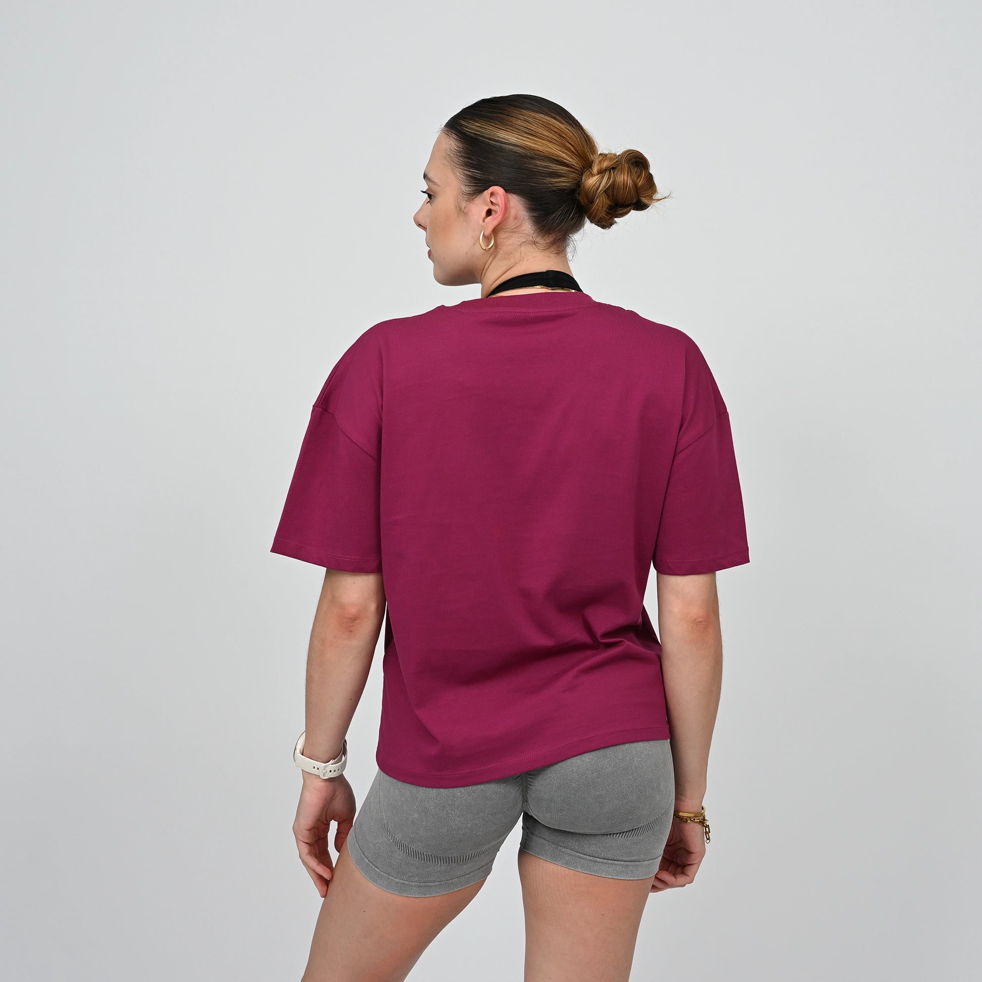 Person wearing a maroon t-shirt and gray shorts on a plain background