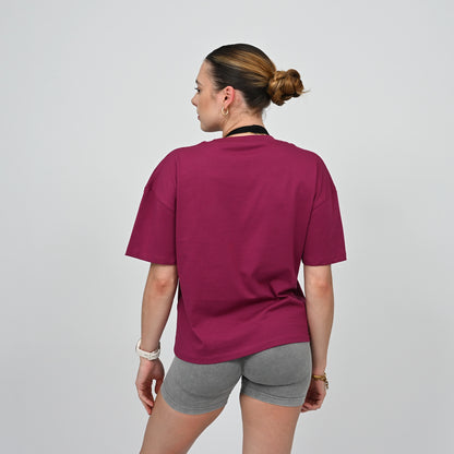 Person wearing a maroon t-shirt and gray shorts on a plain background