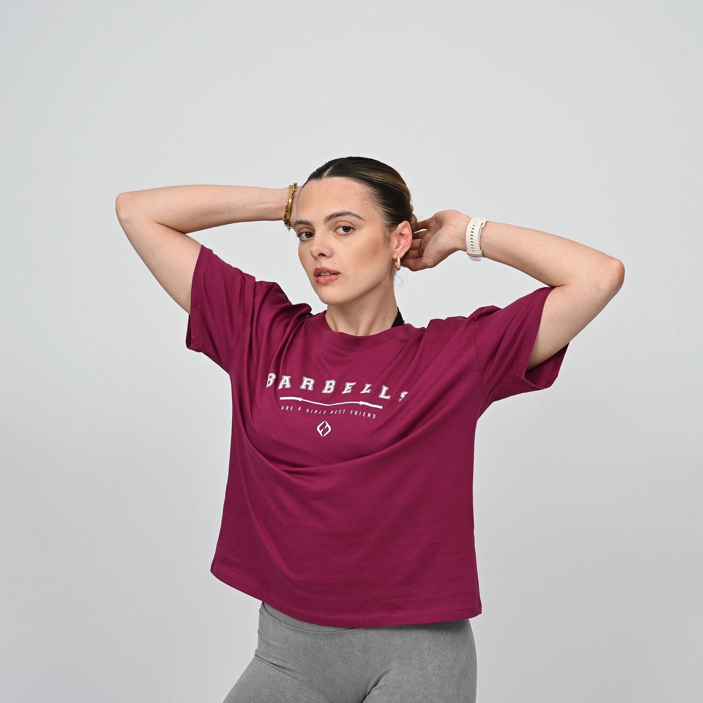 Woman wearing a berry t-shirt with 'Barbells are a girls best friend' logo on it. Boxy tee from Hybryd