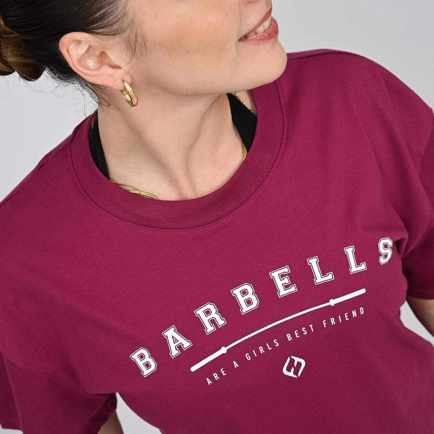 Person wearing a berry t-shirt with 'Barbells are a girl's best friend' text.