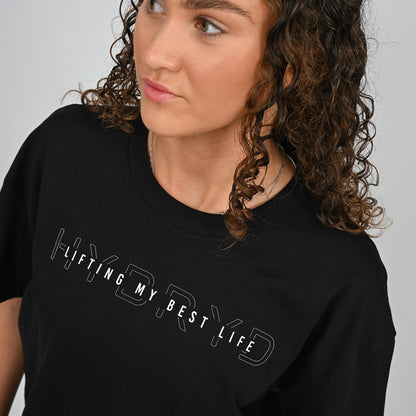 Person wearing a black t-shirt with 'HYBRYD LIFTING MY BEST LIFE' text on a plain background