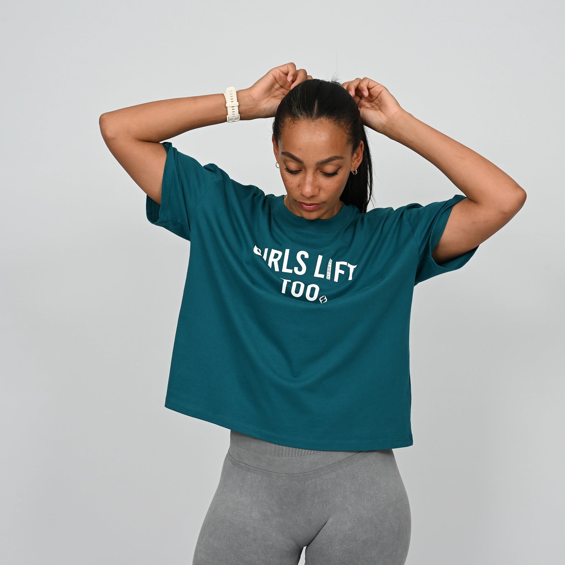 Woman wearing a teal t-shirt with 'GIRLS LIFT TOO' text on From the brand Hybryd