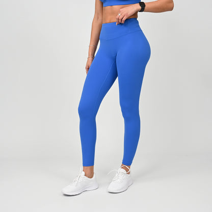 Person wearing blue crossfit workout gym leggings and white sneakers on a gray background