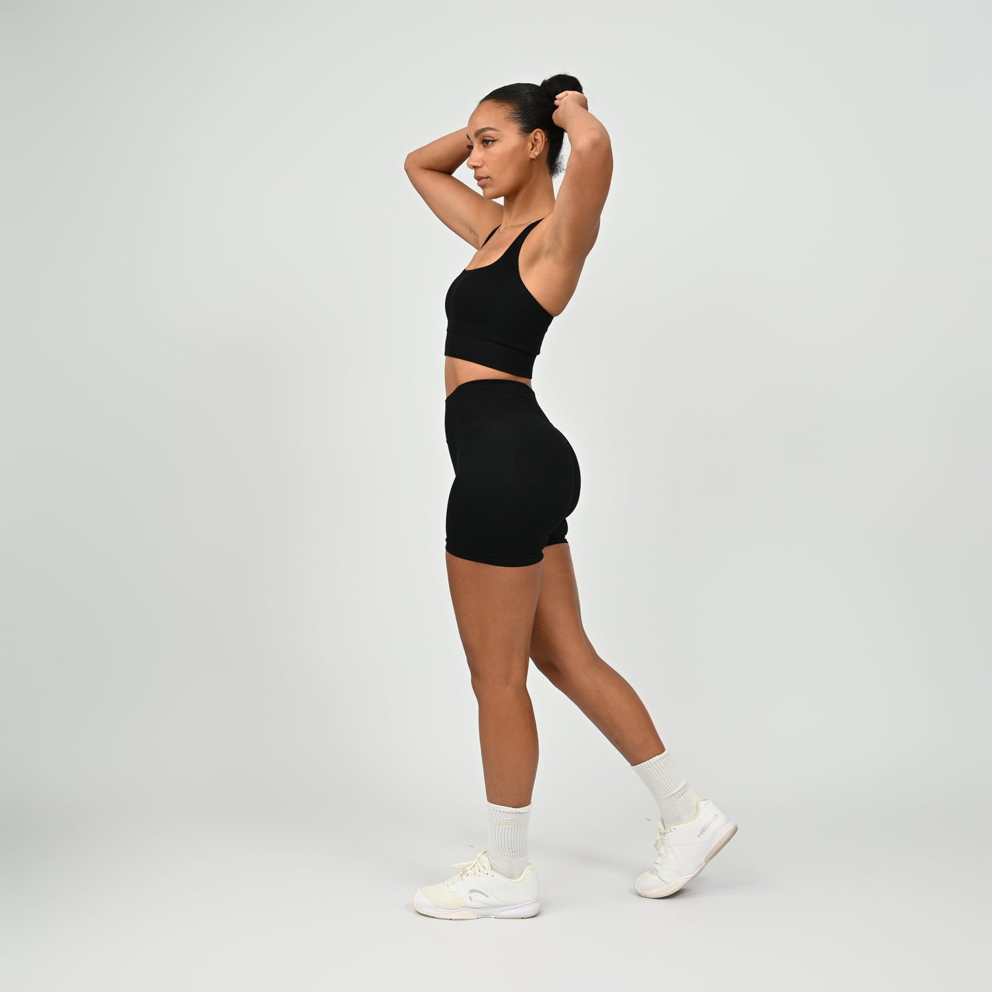 CrossFit athlete wearing a black square neck, muscle back sports bra with matching cinch bum bootie shorts from the gymwear brand Hybryd.