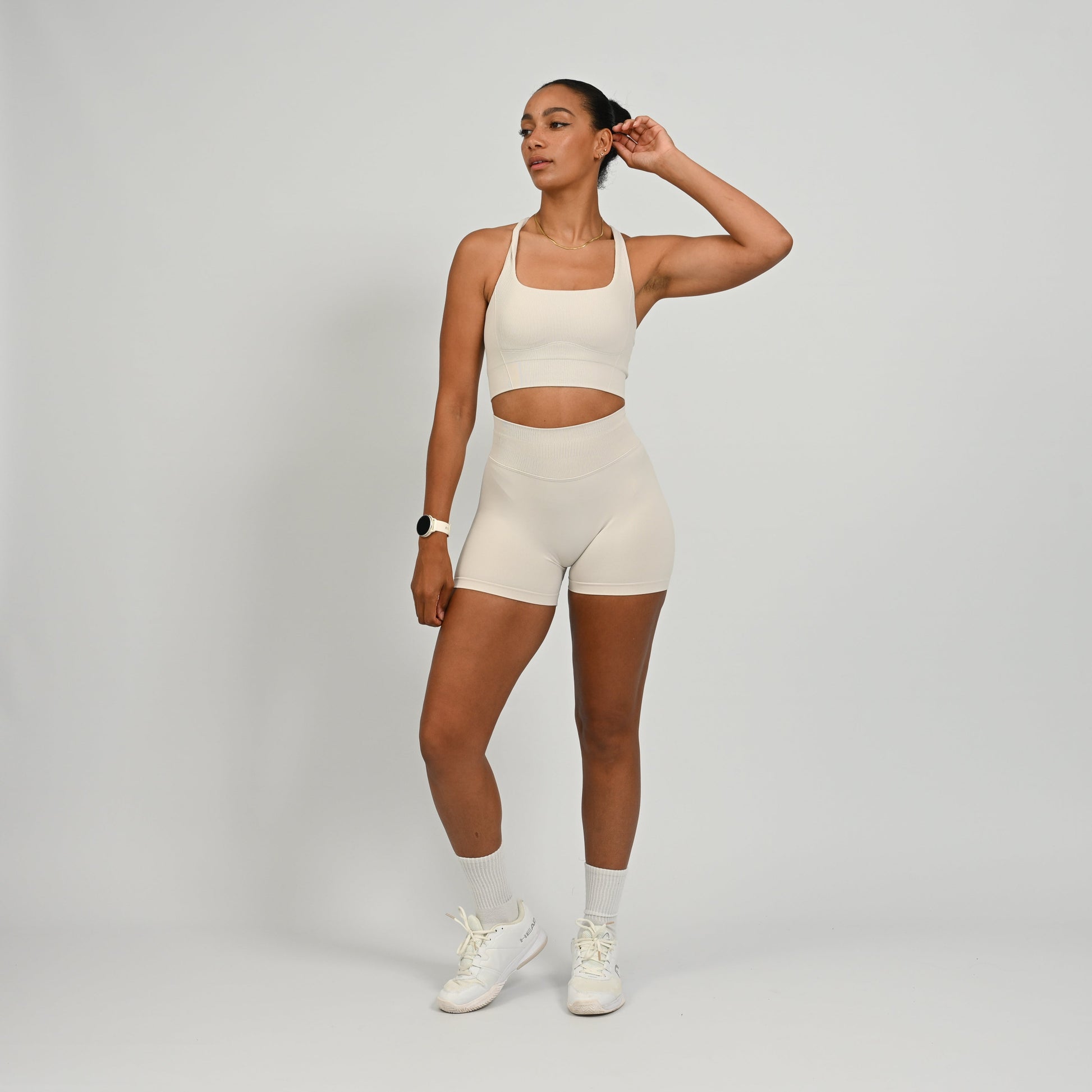CrossFit athlete wearing a off white square neck, muscle back sports bra with matching cinch bum bootie shorts from the gymwear brand hybryd.