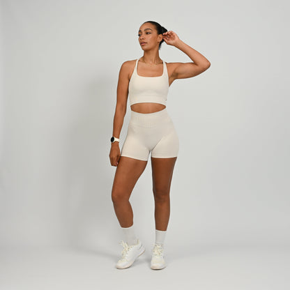 CrossFit athlete wearing a off white square neck, muscle back sports bra with matching cinch bum bootie shorts from the gymwear brand hybryd.