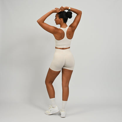 CrossFit athlete wearing a off white square neck, muscle back sports bra with matching cinch bum bootie shorts from the gymwear brand hybryd.