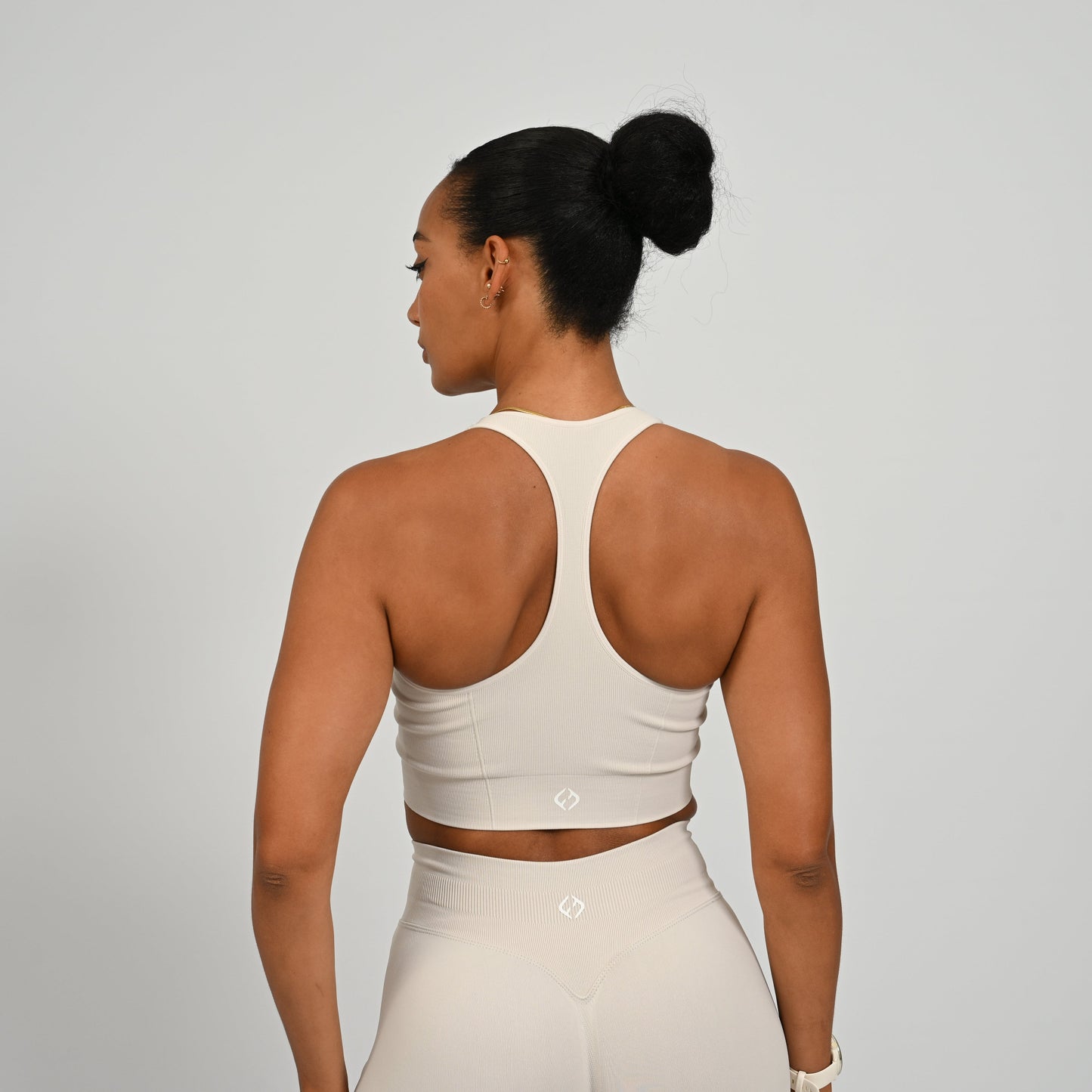 CrossFit athlete wearing a off white square neck, muscle back sports bra with matching cinch bum bootie shorts from the gymwear brand hybryd.