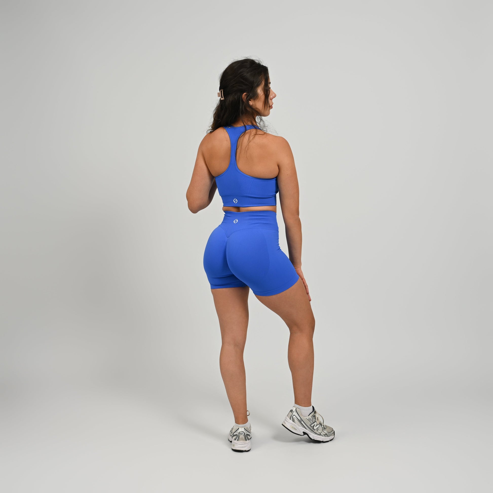 CrossFit athlete wearing a off white square neck, muscle back sports bra with matching cinch bum bootie shorts from the gymwear brand Hybryd.