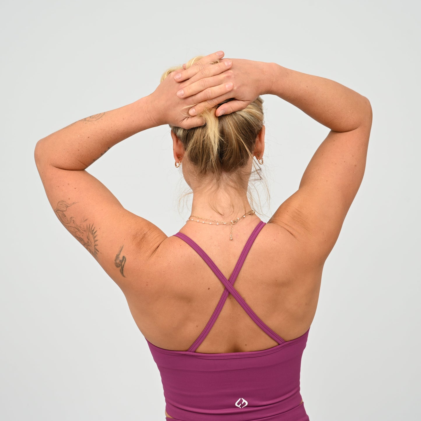 Crossfit girl wearing a purple ribbed workout vest with removable pads and crossover straps. Made by gymwear brand Hybryd