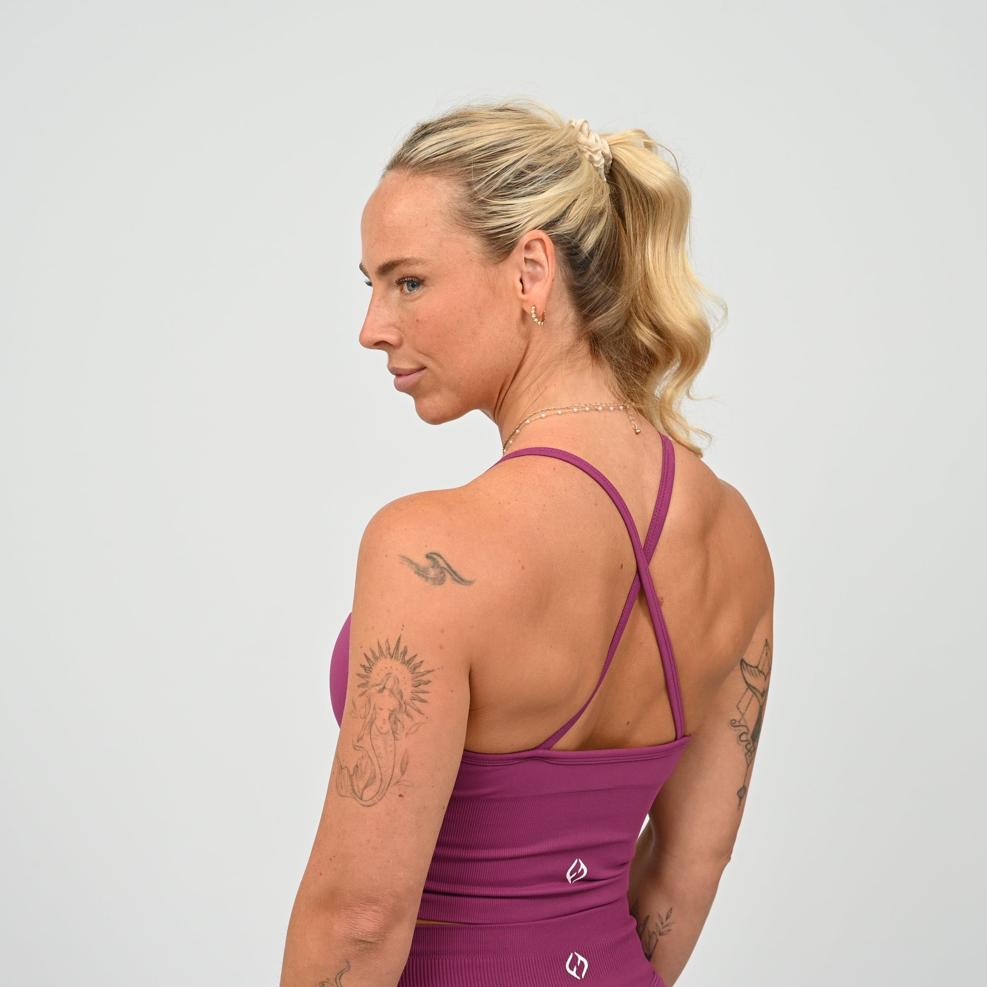 Crossfit girl wearing a purple ribbed workout vest with removable pads and crossover straps. Made by gymwear brand Hybryd