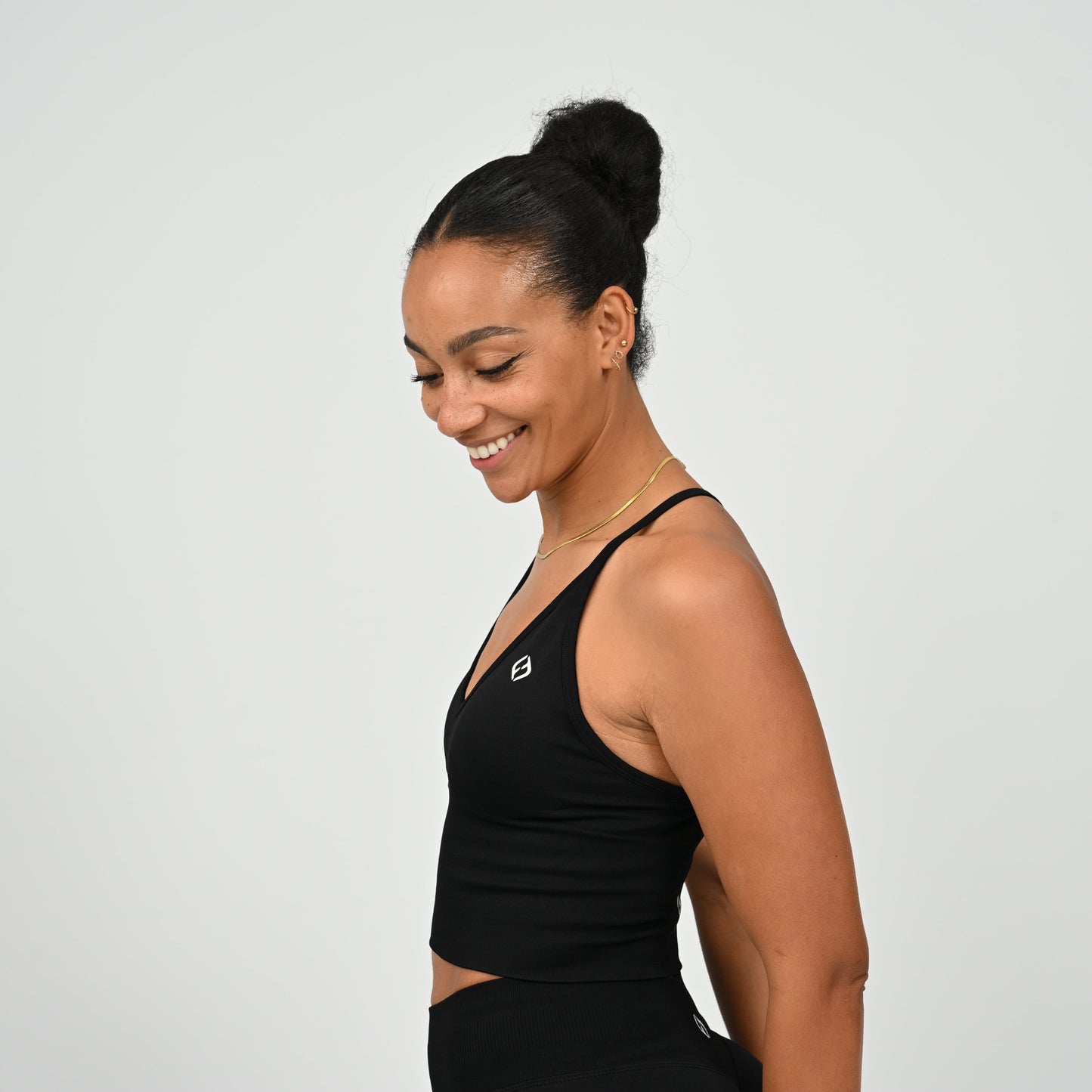 Crossfit girl wearing a black ribbed workout vest with removable pads and crossover straps. Made by gymwear brand Hybryd