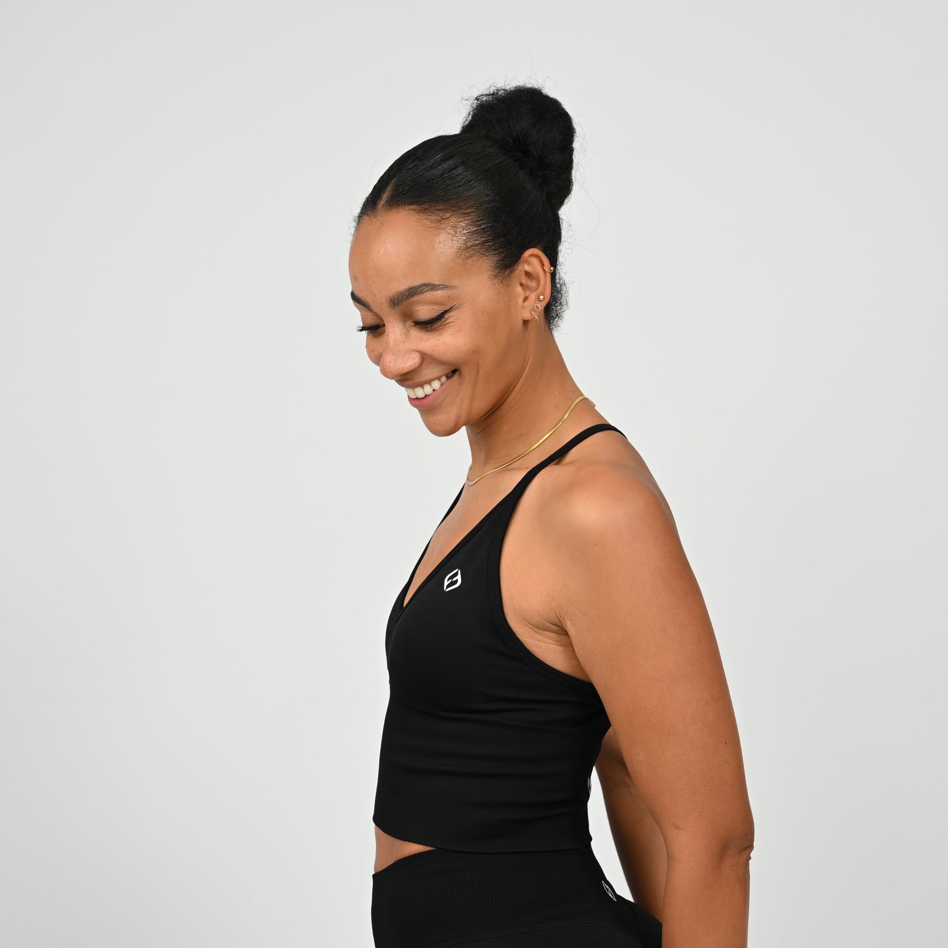 Crossfit girl wearing a black ribbed workout vest with removable pads and crossover straps. Made by gymwear brand Hybryd