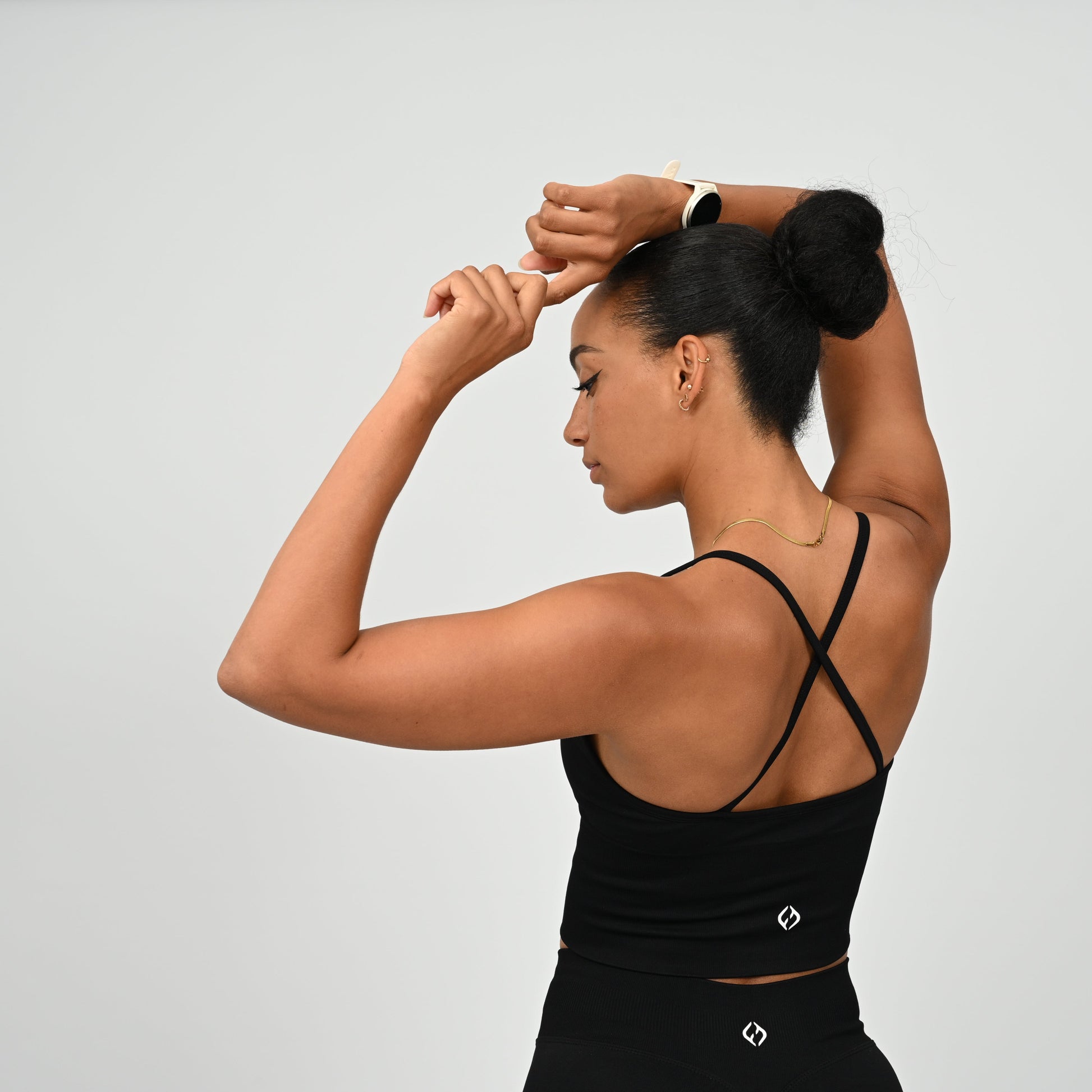 Crossfit girl wearing a black ribbed workout vest with removable pads and crossover straps. Made by gymwear brand Hybryd