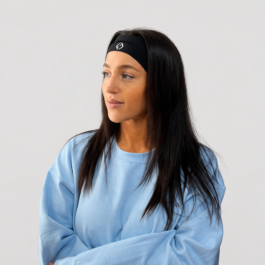 Woman wearing a black headband with a logo on a light gray background