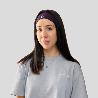 Woman wearing a grey shirt and purple headband with a Hybryd logo on a light gray background
