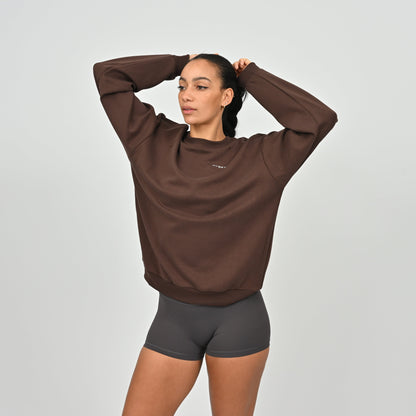 Woman wearing a brown sweatshirt and black shorts from Hybryd on a light gray background