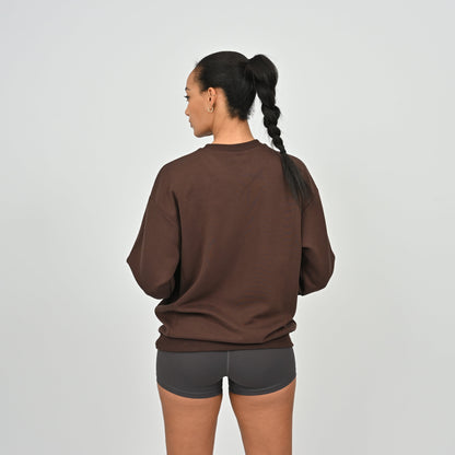 Women wearing a brown sweatshirt and gray shorts from Hybryd activewear on a light gray background