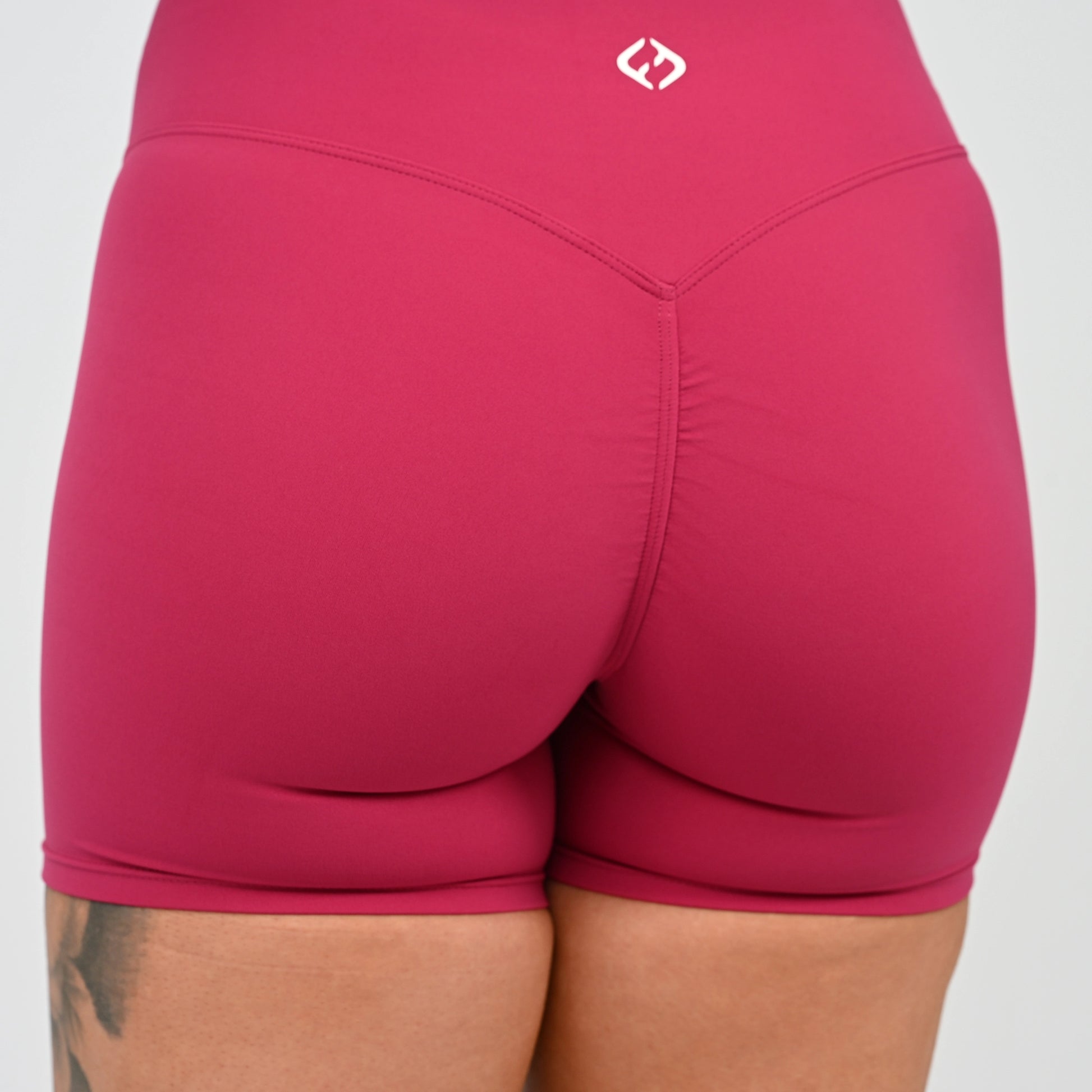 Close-up back view of a person wearing cinch bum shorts with a small white Hybryd logo near the waistband, against a light gray background.