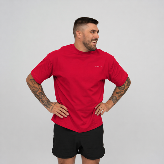 Man wearing a red t-shirt from Hybryd and black shorts on a grey background