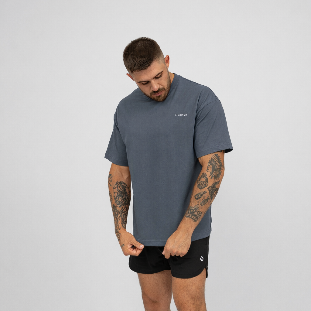 Man wearing a grey Hybryd t-shirt and black shorts on a light gray background