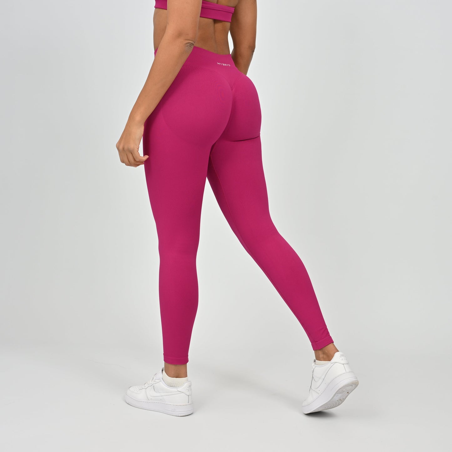 Woman wearing bright pink Hybryd gym leggings and a matching top. 