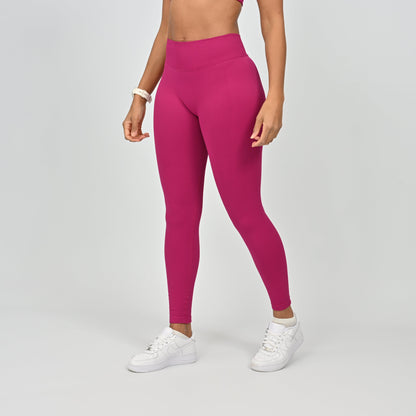 Person wearing bright pink Hybryd gym leggings on a gray background
