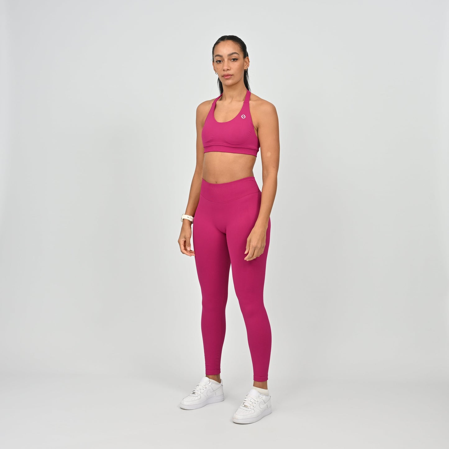 Woman wearing a pink Hybryd sports bra and leggings matching gym set