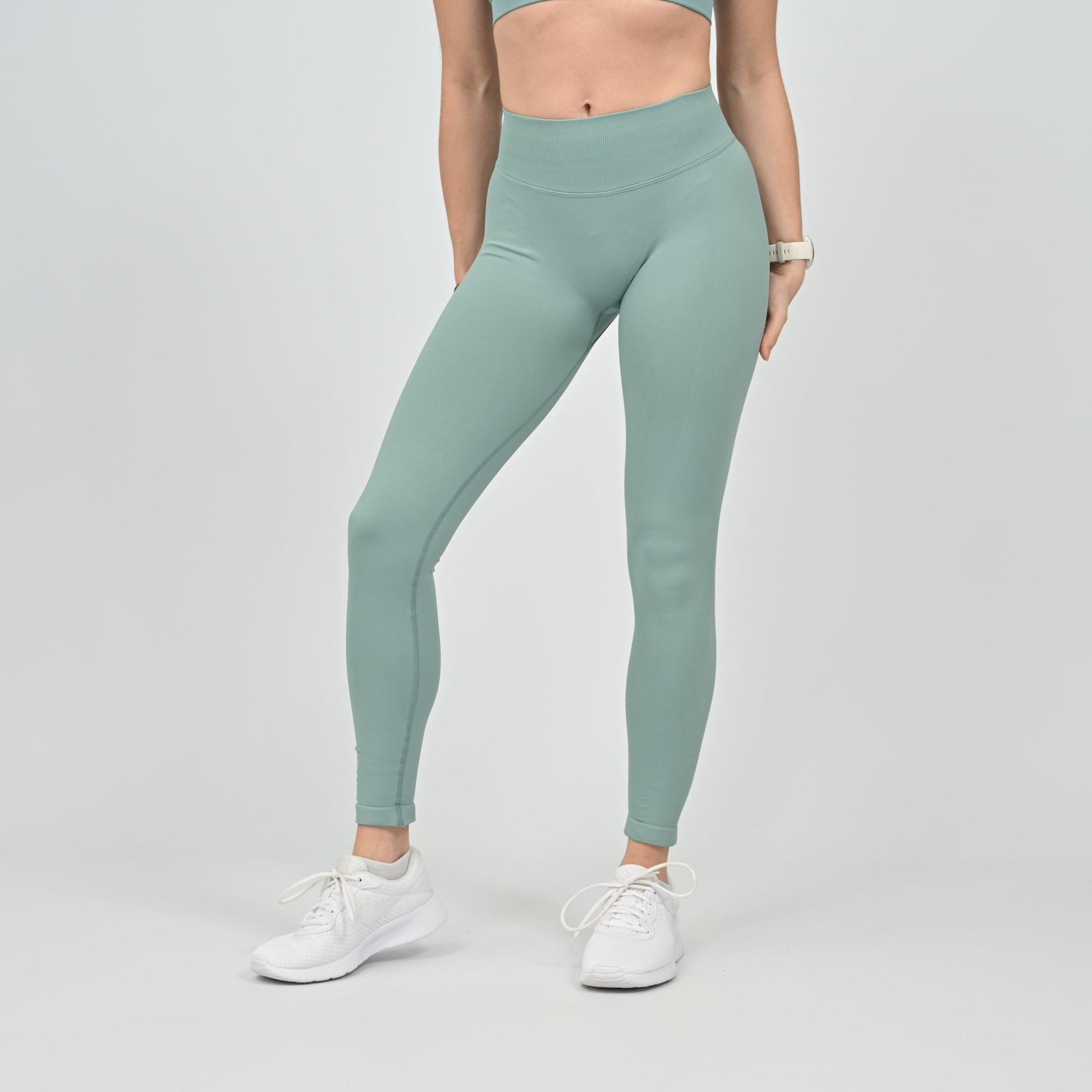 Person wearing Hybryd light green scrunch bum leggings and white sneakers on a plain background