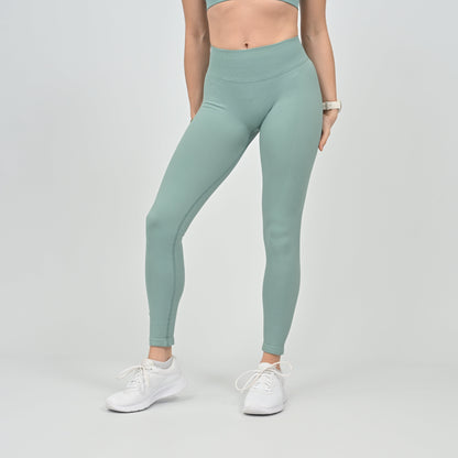 Person wearing Hybryd light green scrunch bum leggings and white sneakers on a plain background