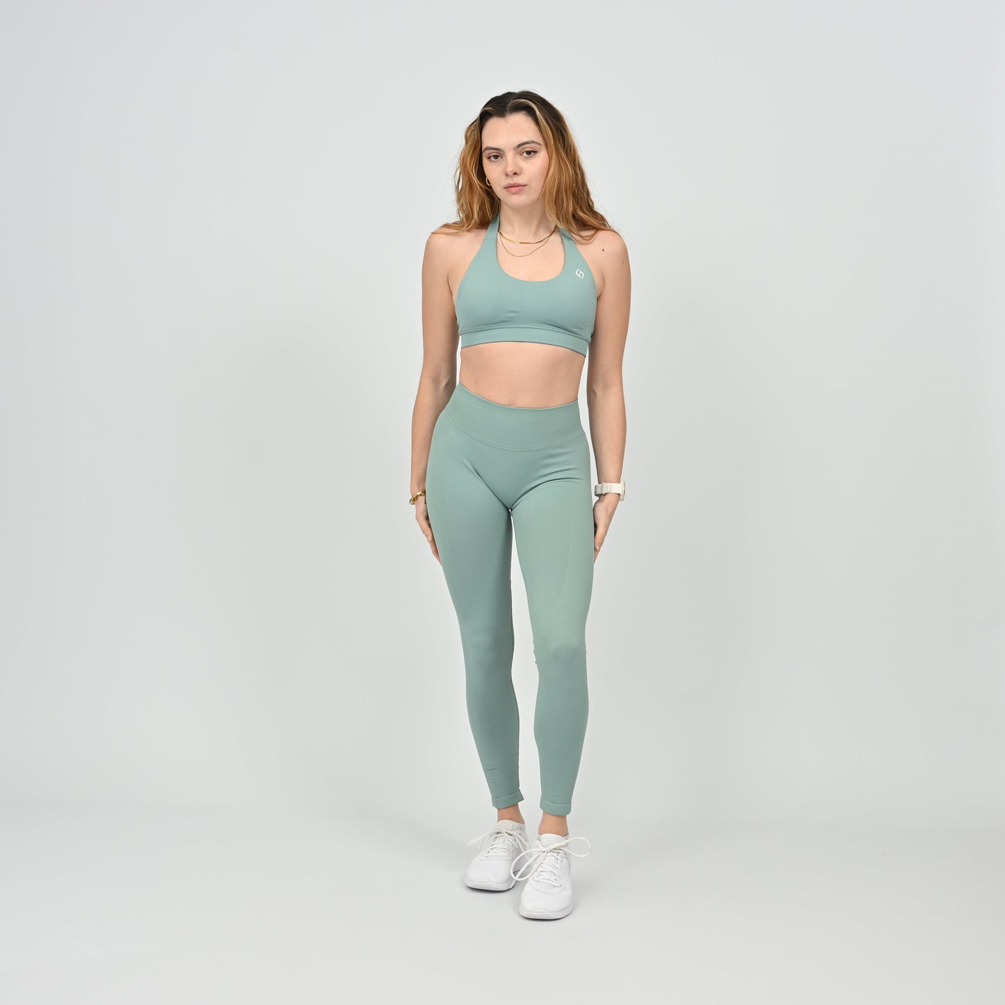 Woman wearing a green halter neck sports bra and leggings from the brand Hybryd