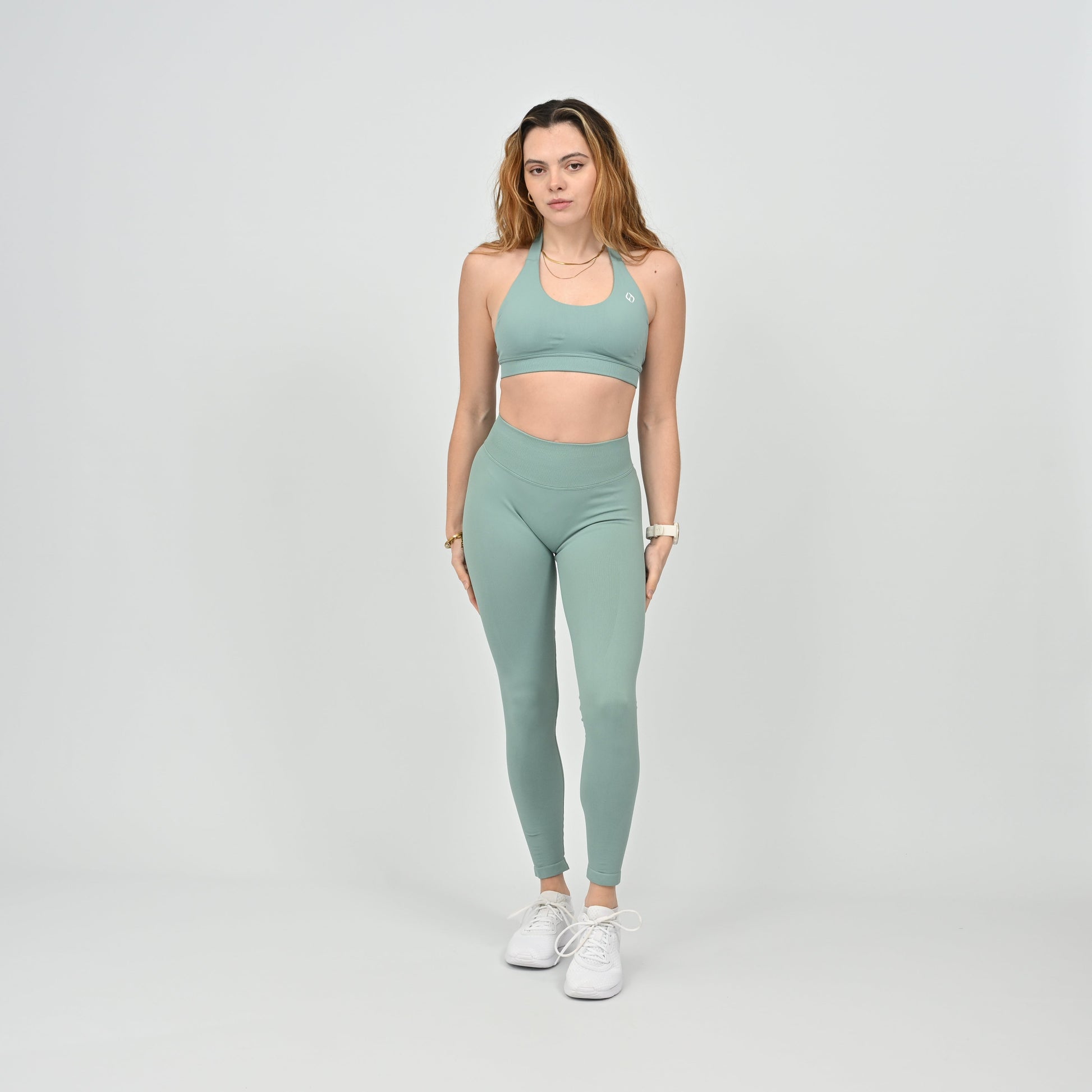 Woman wearing a green halter neck sports bra and leggings from the brand Hybryd