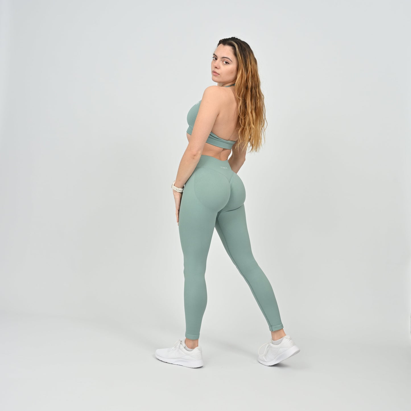 Woman wearing a green matching gymwear set from Hybryd