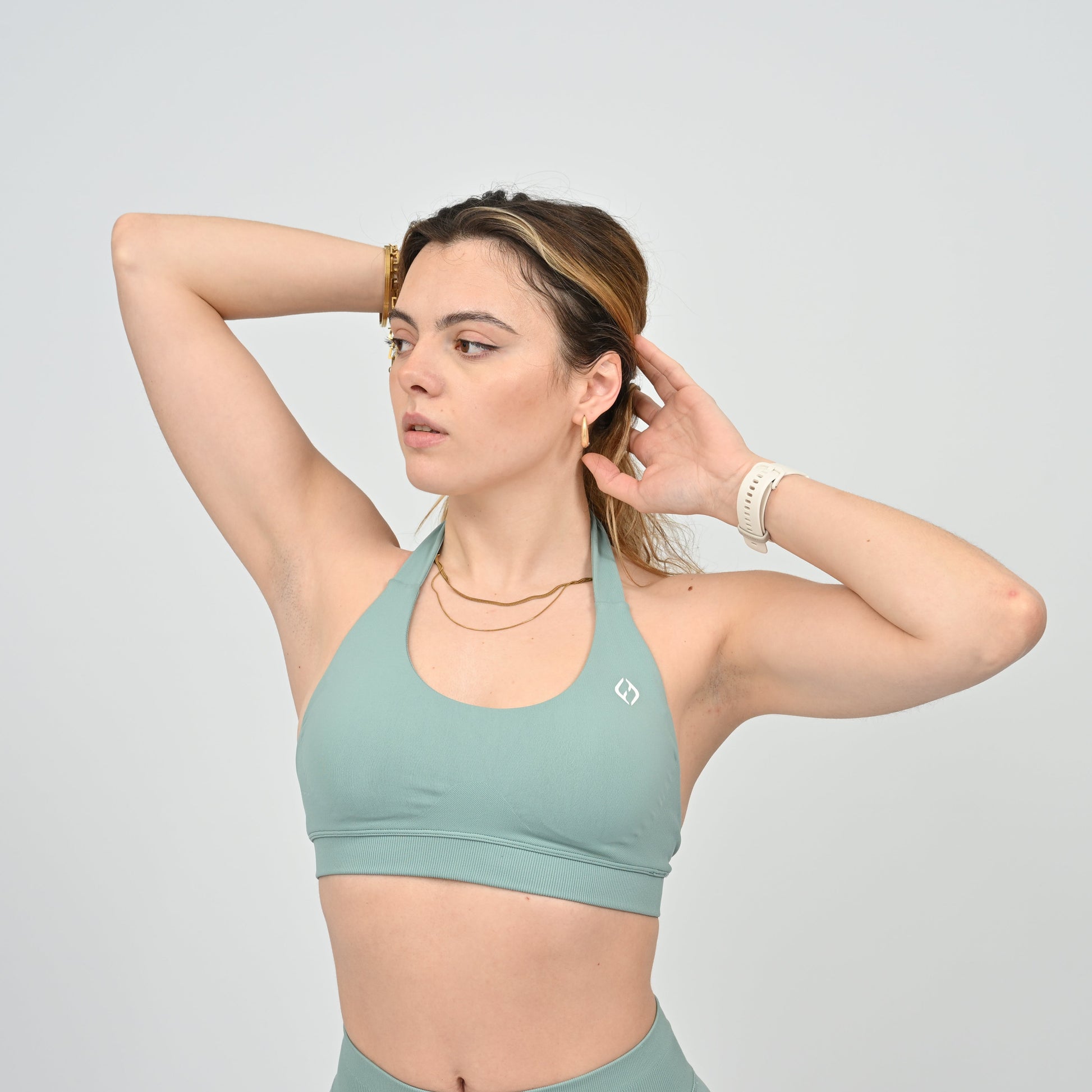 Woman wearing a seafoam sports bra and leggings from Hybryd 