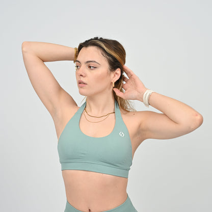 Woman wearing a seafoam sports bra and leggings from Hybryd 