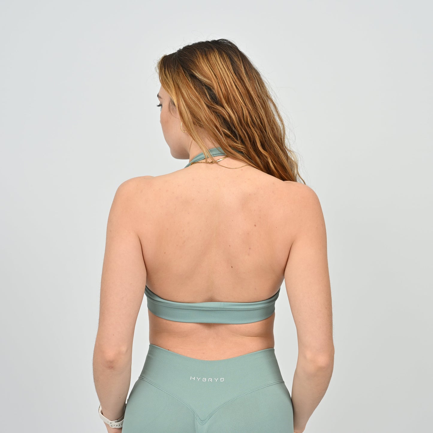 Woman wearing a seafoam sports bra and leggings from actiewear brand Hybryd