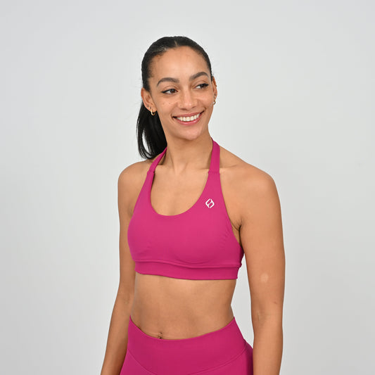 Woman wearing a pink Hybryd sports bra and matching leggings with a logo on the front