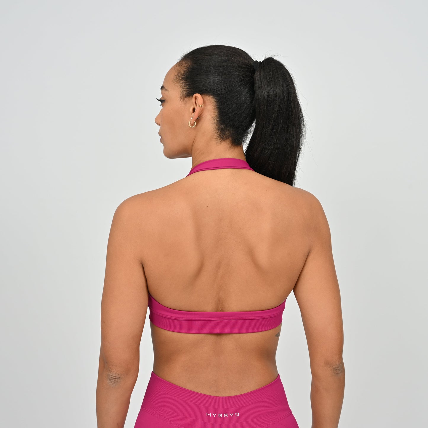 Woman wearing a pink Hybryd sports bra and gym leggings.