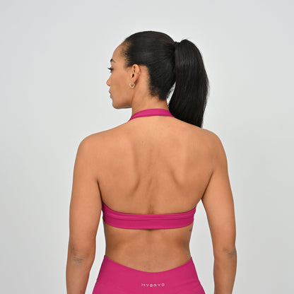 Woman wearing a pink Hybryd sports bra and gym leggings.