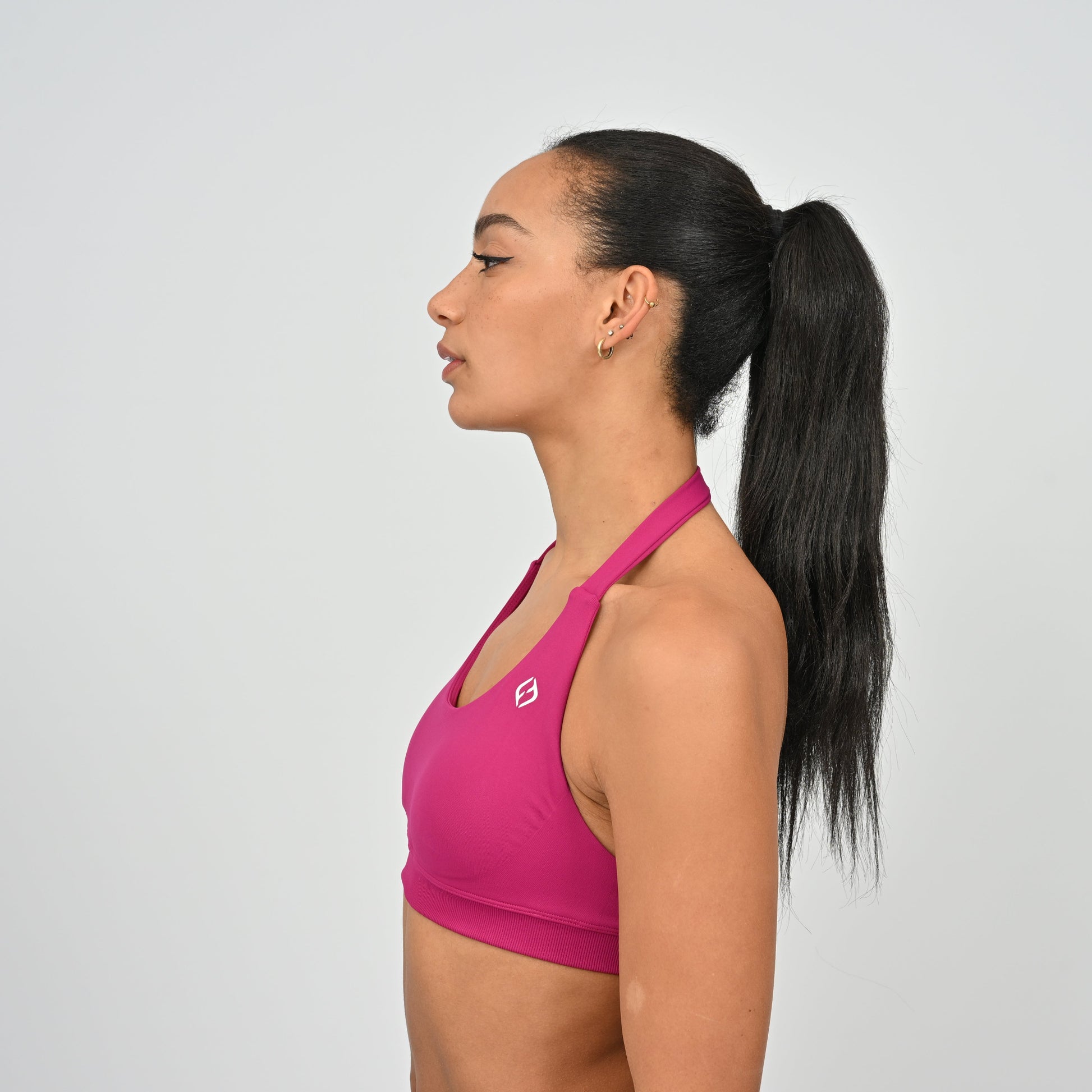 Woman wearing a pink sports bra with a white Hybryd logo.