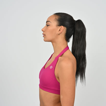 Woman wearing a pink sports bra with a white Hybryd logo.