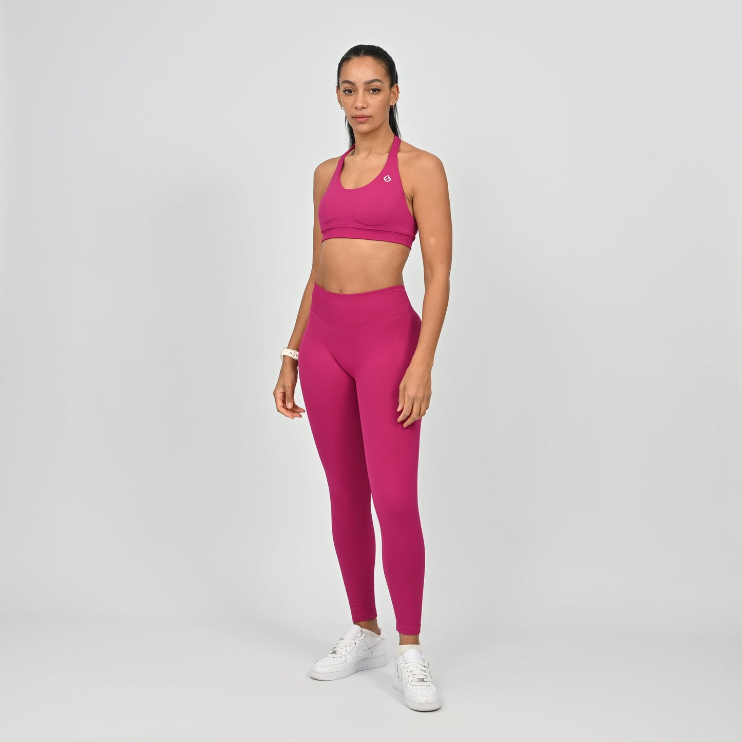 Woman wearing a pink matching gymwear set from the brand Hybryd