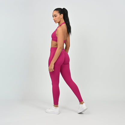 Woman wearing a pink athletic outfit on a white background form the activewear brand Hybryd