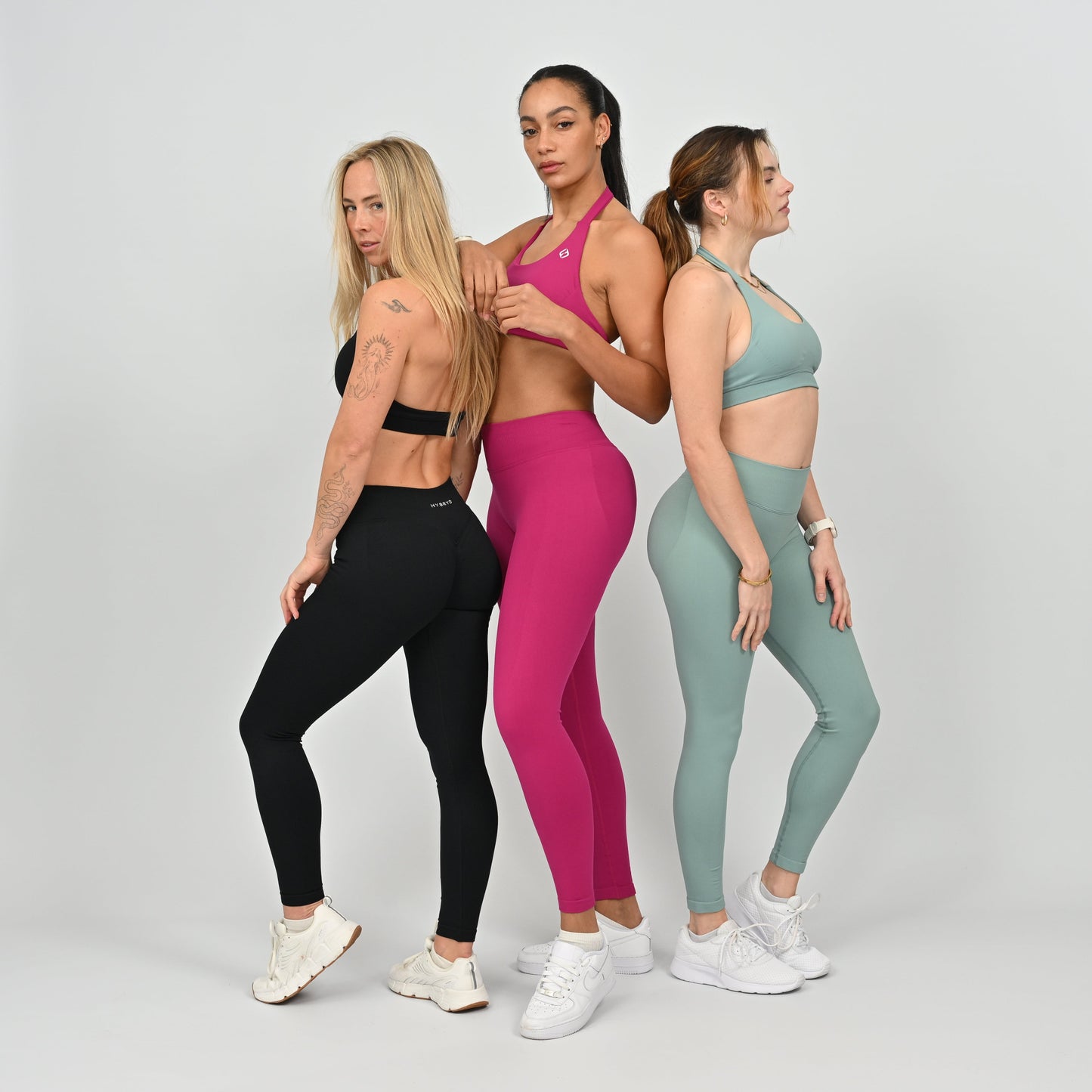 Three women wearing colorful athletic wear from Hybryd. 