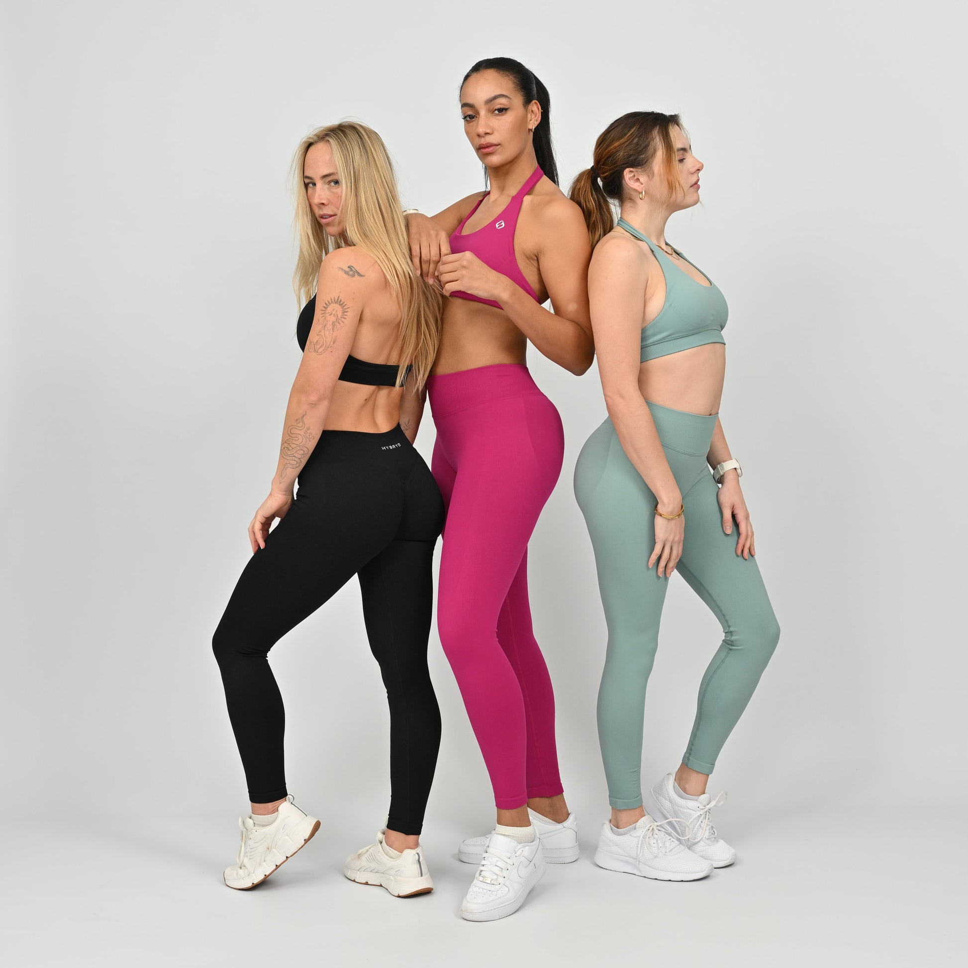 Three women wearing colorful athletic wear from Hybryd. 